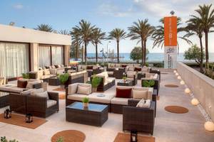 Loungebereich des HM Gran Fiesta Hotels mit Blick auf den Ozean und Palmen.