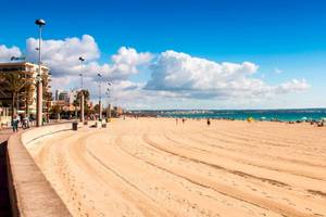 Strand am HM Gran Fiesta Hotel mit einigen Besuchern und Palmen.