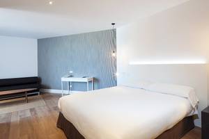 Innenansicht eines Schlafzimmers im HM Gran Fiesta Hotel mit einem Bett, Möbeln und einer Wandgestaltung.