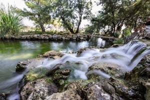 Ein Wasserfall fließt über Felsen in einem waldreichen Gebiet nahe dem Niko Hotel.
