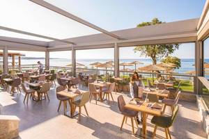 Innenansicht des Restaurants im Cactus Mare Hotel mit Blick auf das Meer und Sonnenschirme.