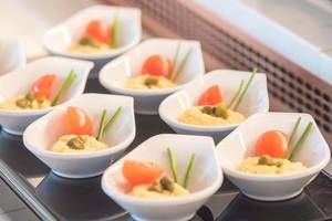 Buffet mit kleinen Schüsseln gefüllt mit gelbem Hummus und Tomatenstücken im Cactus Mare Hotel