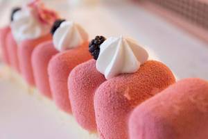 Reihe von rosa Desserts mit weißer Creme und schwarzen Beeren oben, im Cactus Mare Hotel.