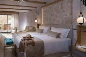 Doppelbett-Zimmer im Hotel Cactus Mare mit steinerner Wand, Deckenventilator und Lampen.
