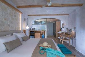 Innenansicht eines Schlafzimmers im Cactus Mare Hotel mit Bett, Schreibtisch, Kleiderschrank und Deckenventilator.