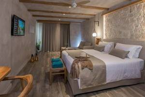 Innenansicht eines Zimmers im Cactus Mare Hotel mit Bett, Fernseher und Holzmöbeln.