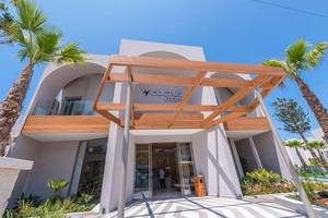 Eingang des Cactus Mare Hotels mit Holzüberdachung und Palmen im Vordergrund