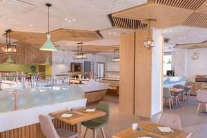 Innenansicht des Cactus Mare Hotel Restaurants mit Holzelementen, hängenden Lampen und gedeckten Tischen.