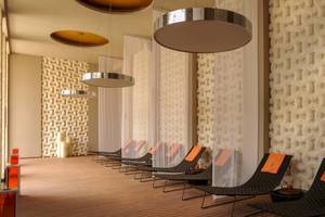 Spa-Lounge im Paradisus Playa del Carmen Hotel mit mehreren schwarzen Liegen und orangefarbenen Kissen.