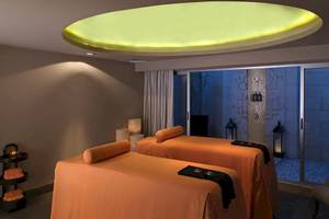 Spa-Behandlungsraum im Paradisus Playa del Carmen mit zwei Massageliegen und einem großen Fenster.