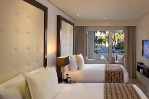 Hotelzimmer im Paradisus Playa del Carmen mit zwei Betten, Fernseher, Lampen und Aussicht auf den Außenbereich.