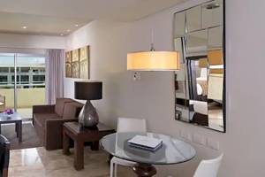 Innenansicht der Suite im Paradisus Playa del Carmen mit Wohnzimmer, Essbereich und Balkon.