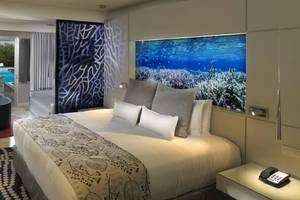 Innenansicht eines Hotelzimmers im Paradisus Playa del Carmen mit einem großen Bett, Fernseher und Poolblick.