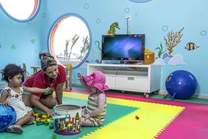 Eine Frau und zwei Kinder spielen in einem farbenfrohen Spielzimmer des Melia Marina Varadero Hotels.