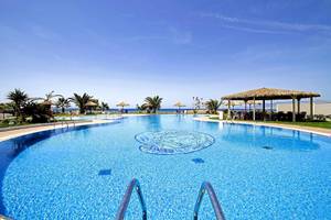Pool im Plaza Beach Hotel mit Blick auf das Meer und Sonnenschirmen.