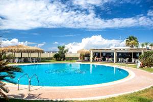 Außenpoolbereich des Plaza Beach Hotels mit Liegestühlen und Sonnenschirmen.