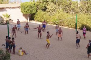 Gruppe von Männern und Frauen spielen Volleyball auf einem sandigen Strand am Sea Star Beau Rivage Hotel.