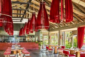 Innenraum des Long Beach Mauritius Restaurants mit roten Vorhängen und Lampen.