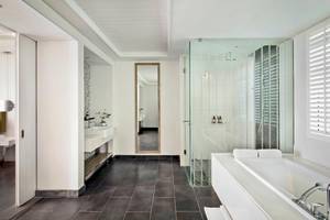 Das Badezimmer im Long Beach Mauritius Hotel mit weißem Wanne, Glasdusche und Waschbecken.