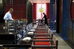 Ein Hotelrestaurant mit roten Stühlen und Tisch, an dem ein Kellner bedient.