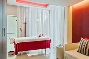 Massageraum im Long Beach Mauritius Hotel mit rotem Massagetisch und weißen Vorhängen.
