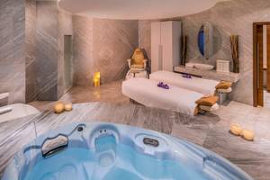 Spa-Bereich im Retreat Palm Dubai MGallery by Sofitel mit Whirlpool, Massageliegen und Marmorboden.
