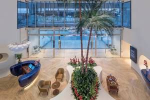 Innenansicht der Lobby im The Retreat Palm Dubai MGallery by Sofitel mit hohen Glaswänden, Pflanzen und Möbeln.