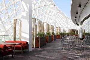 Außenterrasse des W Abu Dhabi Hotels auf Yas Island mit Tischen, Stühlen und roten Sesseln.