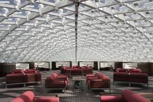 Loungebereich des W Abu Dhabi Hotels auf Yas Island mit roten Sesseln und weißer Dachstruktur.