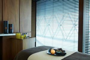 Behandlungsraum im W Abu Dhabi - Yas Island mit Massageliege, Kerzen und Produkten.