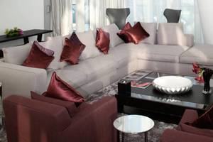 Modernes Wohnzimmer mit großem Sofa, roten Kissen und Glastisch im W Abu Dhabi - Yas Island Hotel.