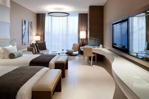 Hotelzimmer im W Abu Dhabi auf Yas Island mit zwei Betten, Wohnzimmerbereich und Fernseher.