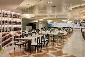 Innenansicht des Restaurants im H10 Timanfaya Palace Hotel mit gedeckten Tischen, Weinflaschen an der Wand und Kronleuchtern.