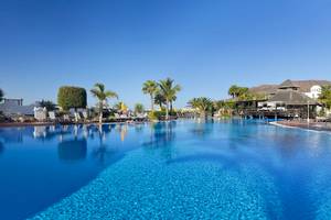 Außenpool des H10 Timanfaya Palace Hotels mit Lounge-Sesseln und Sonnenschirmen.