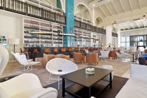 Loungebereich im H10 Timanfaya Palace Hotel mit weißen Möbeln und einer zentralen Bar.