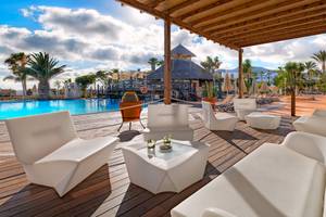 Außenterrasse des H10 Timanfaya Palace mit weißen Möbeln und einem Pool im Hintergrund.