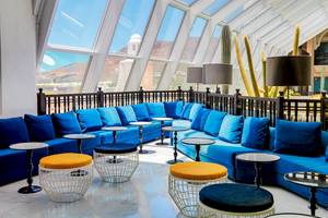 Loungebereich des H10 Timanfaya Palace Hotels mit blauen Sofas, orangen Hockern und Tischen.