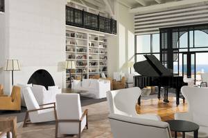 Lobby des H10 Timanfaya Palace mit weißen Sofas, einem Klavier und Blick auf das Meer.