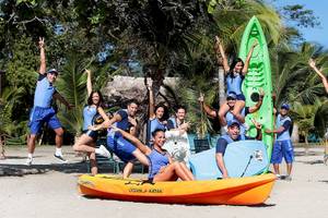 Gruppe von Mitarbeitern des Barcelo Tambor Hotels posiert mit Kajaks am Strand.
