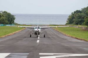 Ein Flugzeug auf dem Rollweg eines Flugplatzes mit dem Meer im Hintergrund.