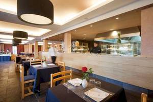 Innenansicht des Blau Punta Reina Hotel Restaurants mit Tischen, Stühlen und Blumen.