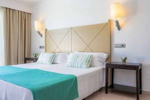 Schlafzimmer im Blau Punta Reina Hotel mit Doppelbett, Nachttischen und Wandleuchten.