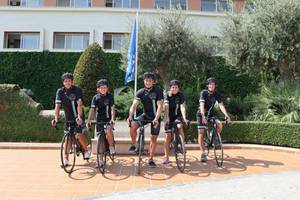 Gruppe von Radfahrern vor dem Blau Punta Reina Hotel, alle in Radsporttrikots gekleidet.