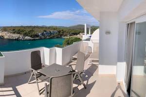 Blick vom Balkon des Blau Punta Reina Hotels auf das Meer und eine Klippe.