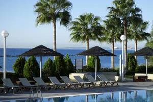 Außenpoolbereich des Atlantica Miramare Beach Hotels mit Palmen, Sonnenliegen und Blick auf das Meer.
