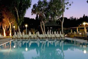 Abendansicht des Schwimmbeckens im Atlantica Miramare Beach Hotel mit illuminierten Liegen und Schirmen