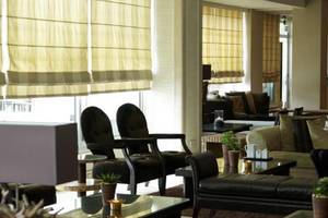 Frau sitzt in der Lobby des Atlantica Miramare Beach Hotel mit Kaffeetasse