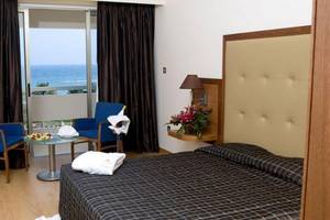 Zimmer im Atlantica Miramare Beach Hotel mit Meerblick, zwei blaue Stühle und ein Tisch