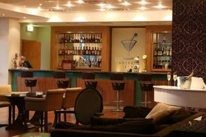 Innenansicht der Bar im Atlantica Miramare Beach Hotel mit Theke, Stühlen und Flaschen.