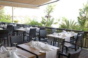 Terrasse des Atlantica Miramare Beach Hotels mit eingerichteten Tischen und Stühlen im Freien.